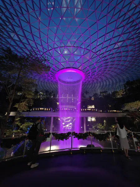 Wodospad pod szklaną kopułą lotniska Jewel Changi, fioletowe światła